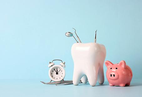 A tooth model with medical instruments, a piggy bank, and a clock on a blue background.