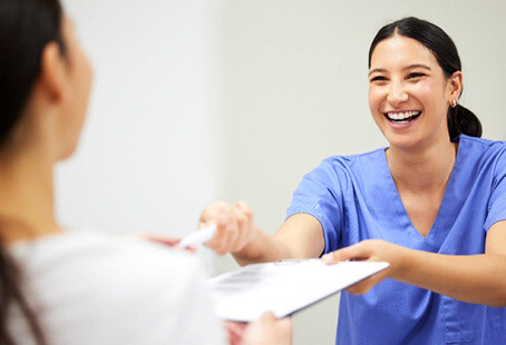 dental assistant smiling while handing patient forms