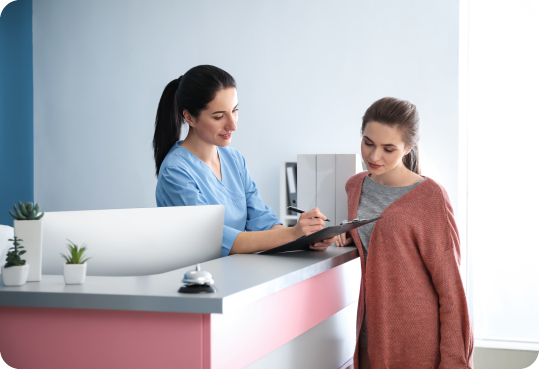 Dental receptionist showing a patient where to sign on clipboard
