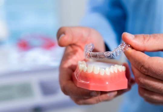Dentist demonstrating Invisalign on model teeth