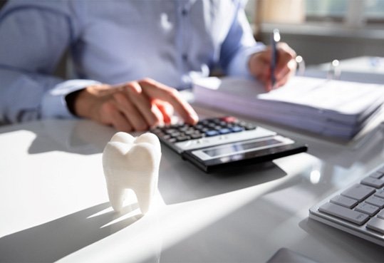 Man at a desk with calculator and fake tooth