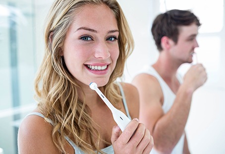 Closeup of woman smiling while holding her toothbrush in bathroom