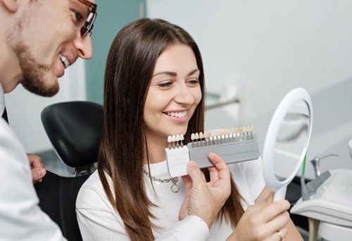 Dentist showing patient shades of veneers in mirror