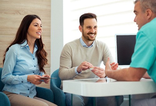 Dentist and couple talking in dental office