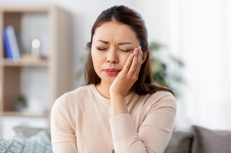 patient with dental emergency holding their cheek