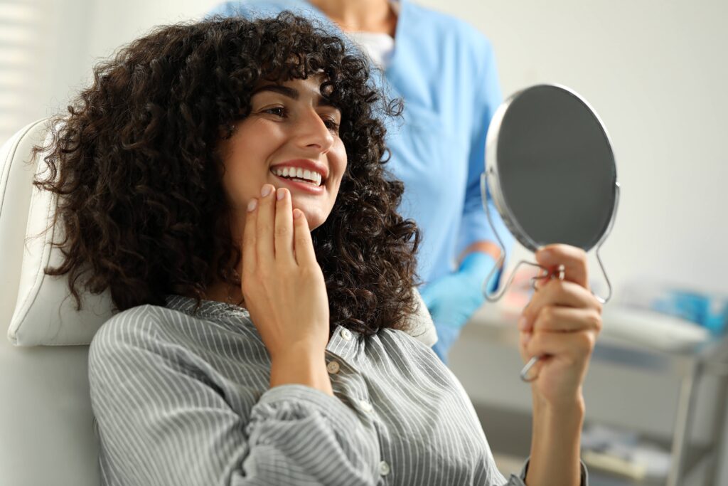 Woman smiling at reflection in handheld mirror